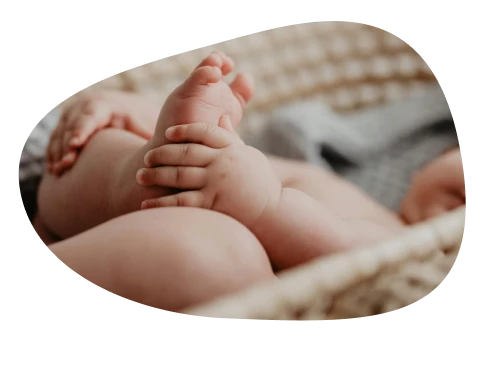 Bebis som håller sin fot och ligger ned i en korg.